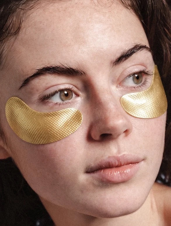 YUTASHA anti-age hydrogel eye patches in gold applied under the eyes of a woman for a firming and hydrating effect