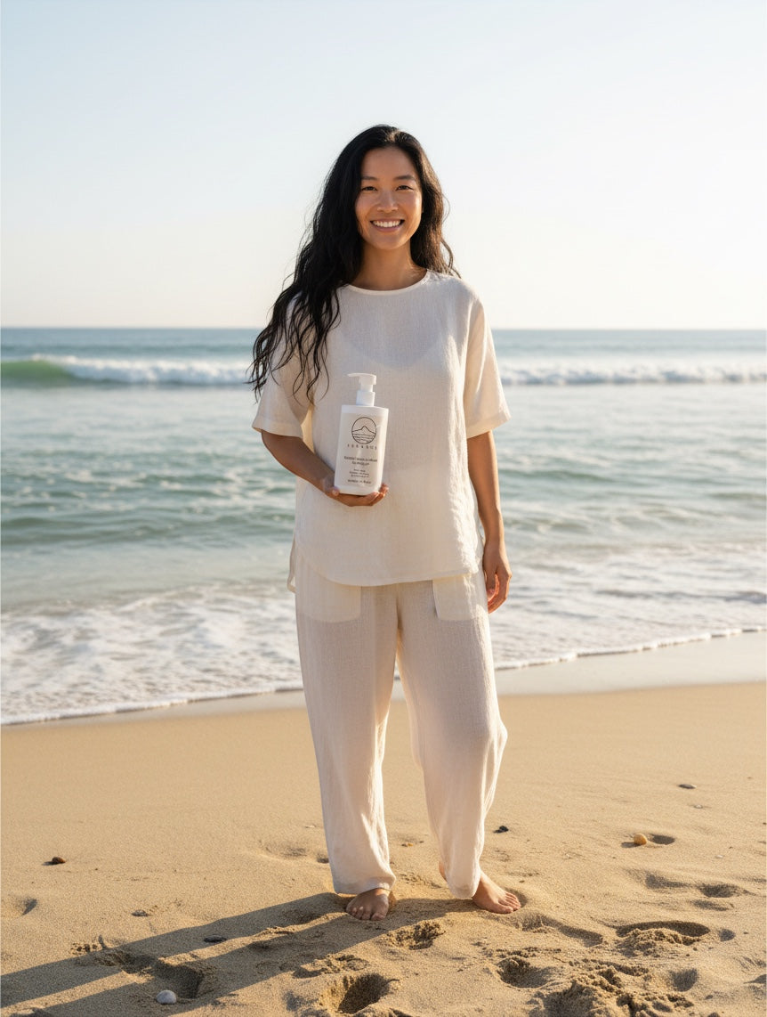 YUTASHA Keratin Volume Boost Shampoo bottle held by a smiling woman in white linen clothing on a sunny beach.