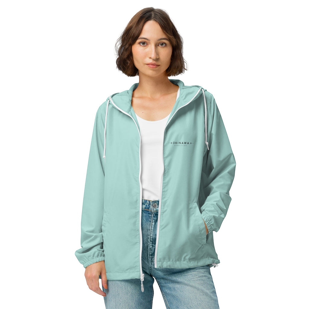 YUTASHA Toshie windbreaker in light teal polyester with a three-panel hood, white zipper, and Okinawa chest print.