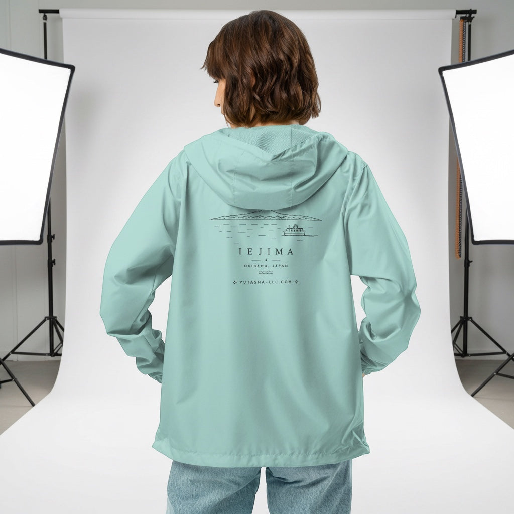 YUTASHA Toshie windbreaker in light mint green with a black Iejima graphic on the back, worn by a model in a studio.